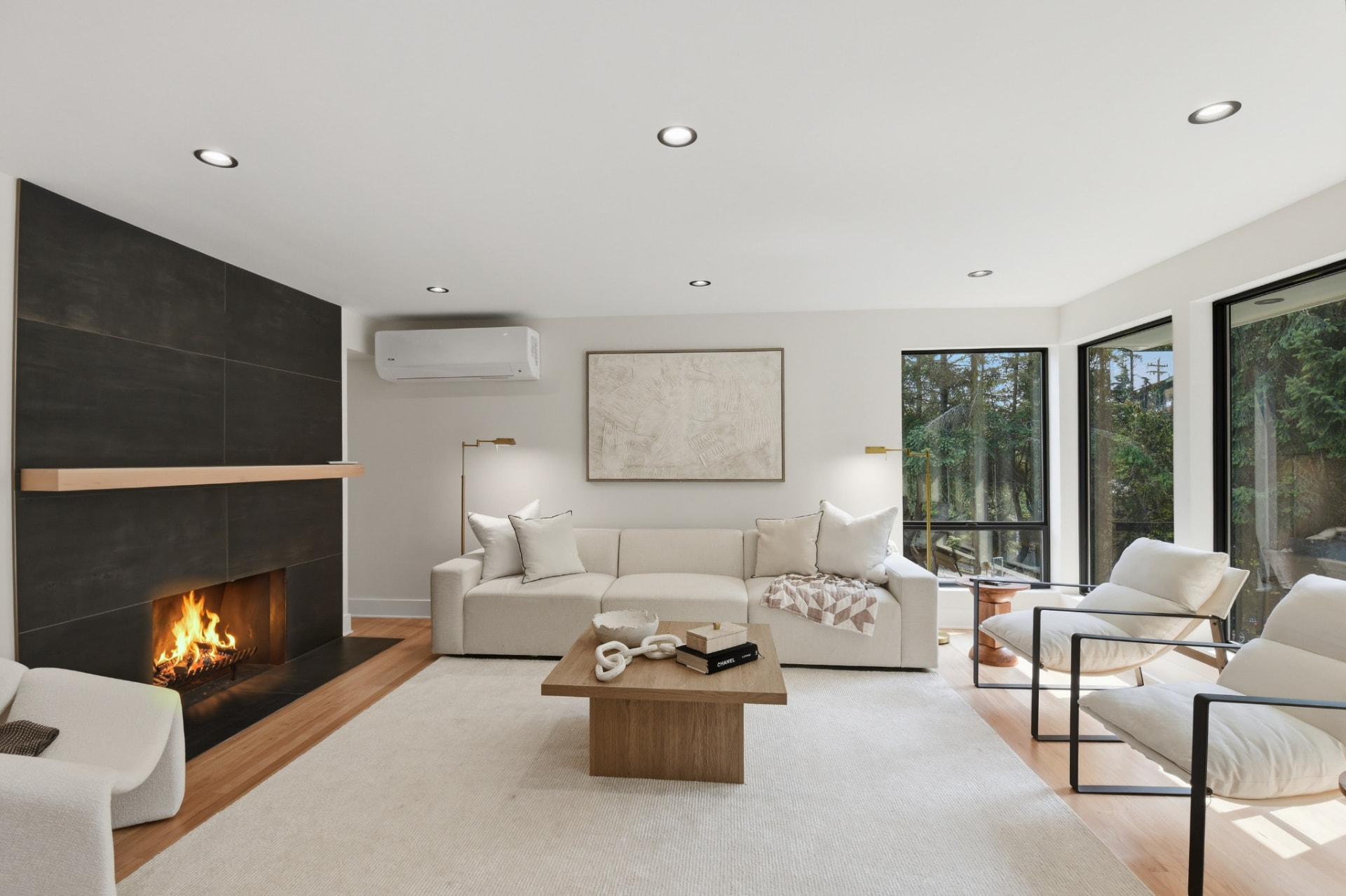 Remodeled living room with black tile fireplace, white sectional sofa and oak floors